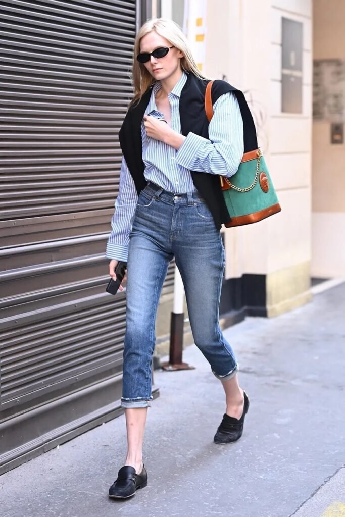 Chic minimalist street style featuring a blue oversized shirt, denim, and black leather loafers—a timeless outfit inspiration for 2026.