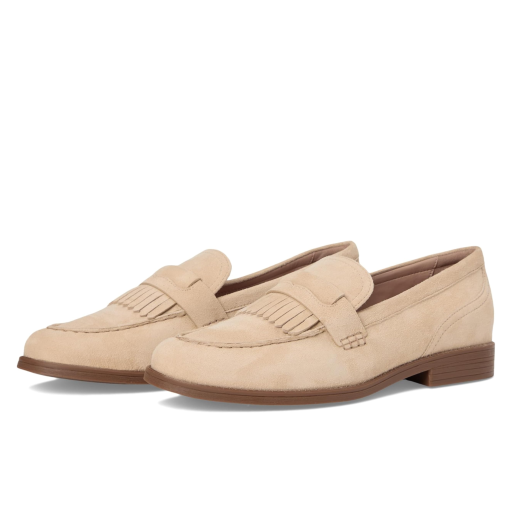 Cole Haan Women's Stassi Kiltie loafers in soft beige suede featuring a classic kiltie fringe detail and a refined almond toe on a white background.
