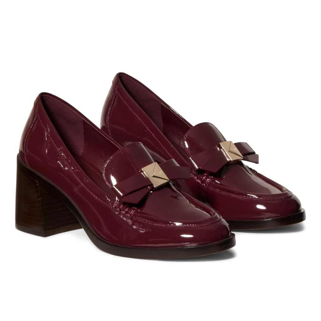 Kate Spade New York Deco Bow heeled loafers in burgundy patent leather featuring a large structured leather bow, square toe, and a mid-height block heel on a white background.