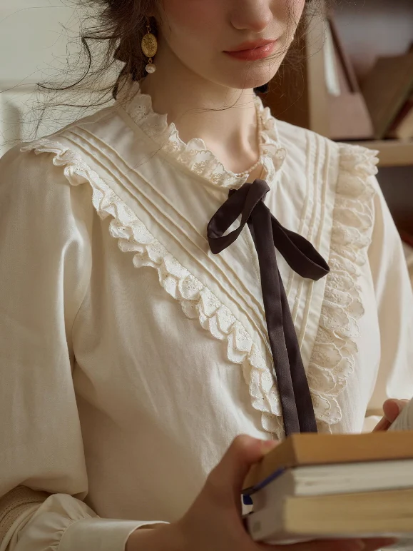 Close-up of a Victorian-style cream bow tie blouse with lace ruffles—a timeless essential for a romantic wardrobe.