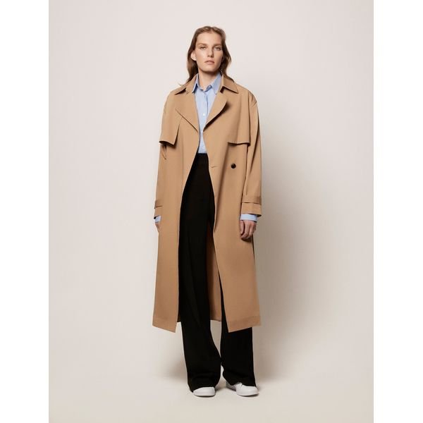 A woman wearing the Another Tomorrow Soft Trench in off-white, featuring a fluid lyocell-cotton blend, flap chest pockets, and a cinched belted waist for a minimalist 2026 look.