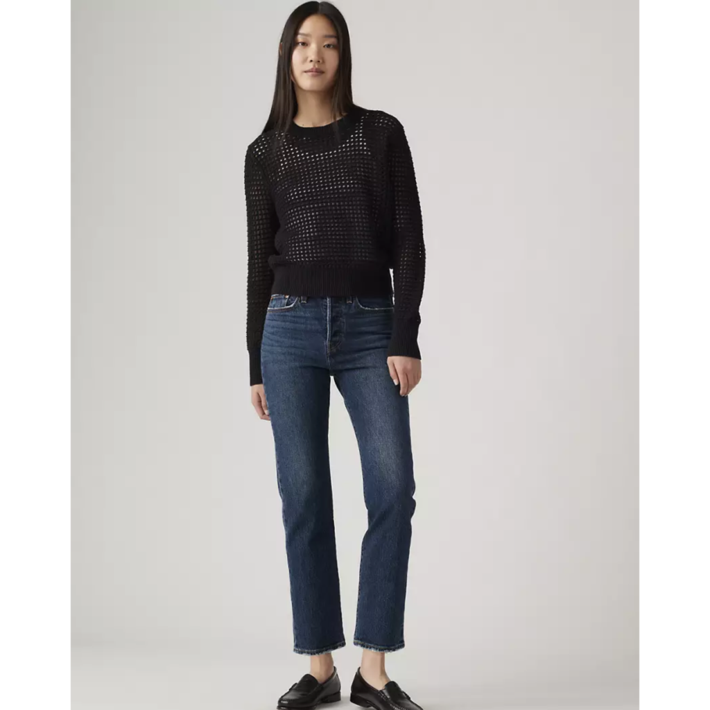 A model wearing Levi’s Wedgie Straight Ankle Jeans in a dark indigo wash, styled with a black crochet long-sleeve top and black loafers for a refined 90s minimalist outfit.